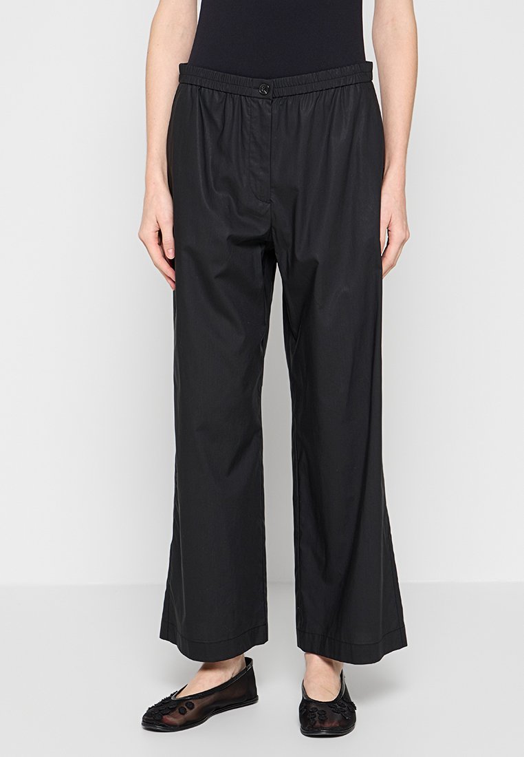 Schwarze, weit geschnittene Hose mit elastischem Bund aus leichtem Material. Glatte Textur mit einem Knopfverschluss vorne. Lässiges Design.