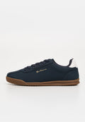Marineblauer Low-Top-Sneaker mit brauner Sohle, weißem Fersenpatch, Schnürsenkeln und goldenem "Ben Sherman" Logo an der Seite, auf weißem Hintergrund dargestellt.