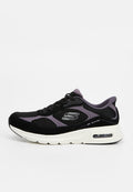 Schwarzer und lila Skechers Slip-On-Sneaker mit weißer Sohle, sichtbarer Luftpolsterung und dem markanten "S"-Logo an der Seite.