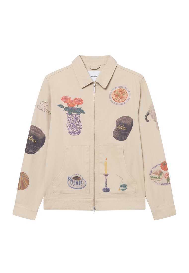 Beige Canvas-Jacke mit verschiedenen künstlerischen Drucken, darunter Blumen, Lebensmittel und Haushaltsgegenstände. Reißverschluss vorne und zwei Fronttaschen.