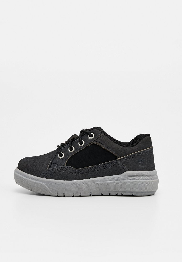 Schwarzer Sneaker mit niedrigem Schaft, grauer Sohle, Schnürsenkeln, gepolstertem Kragen und abgesteppten Details vor neutralem Hintergrund.