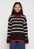 Schwarz-weißer gestreifter Rollkragenpullover mit gerippter Textur, roten Akzenten am Kragen und an den Bündchen sowie lockerem Schnitt.