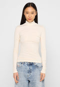 Langärmliges Rollkragenoberteil aus leichtem, strukturiertem Creme-Stoff, mit einer figurbetonten Silhouette und glatter Textur, kombiniert mit hochtaillierten blauen Jeans.