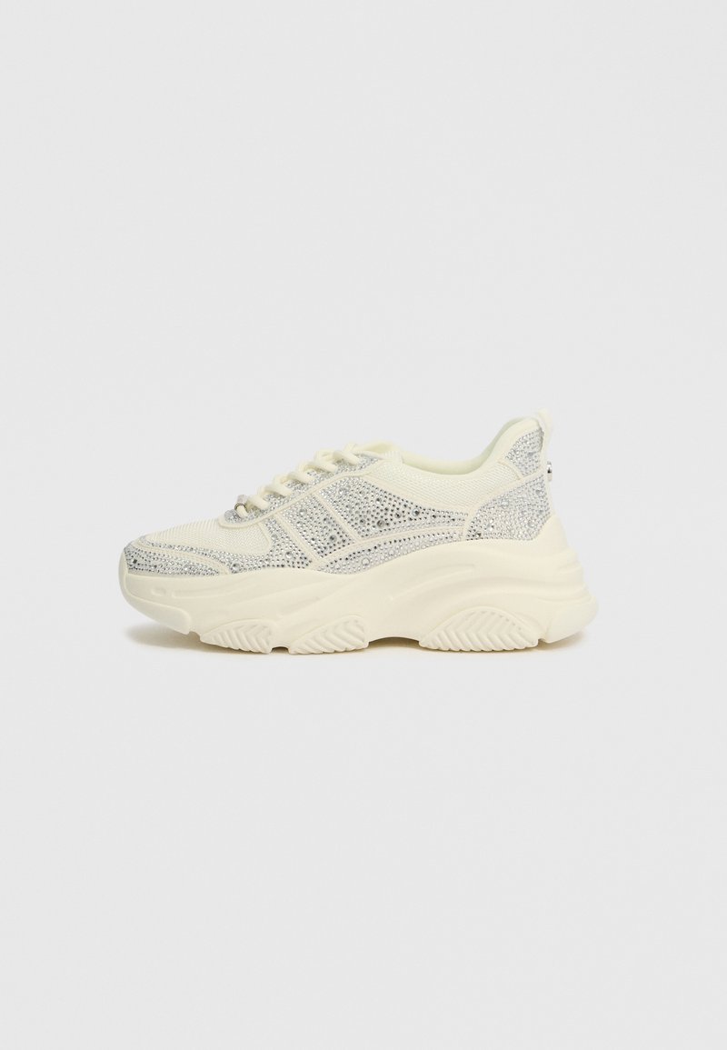 Robuste Sneakers in Creme- und Silbertönen, ausgestattet mit einem strukturierten Stoffoberteil, Schnürdesign und einer dicken Gummisohle.