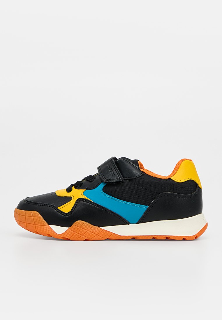 Schwarzer Sneaker mit orangefarbener Sohle, gelben und blauen Akzenten und einem schwarzen Klettverschluss über schwarzen Schnürsenkeln, von der Seite gezeigt.