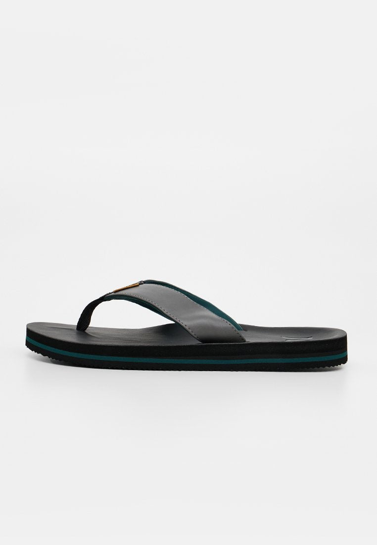 Ein schwarzer und dunkelgrüner Flip-Flop mit dicker Sohle und breitem Riemen in Seitenansicht auf weißem Hintergrund.