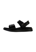 Schwarze Sandalen mit verstellbaren Riemen, glatter Matt-Oberfläche und gepolsterter Sohle. Einfaches Design mit flacher Silhouette und minimalem Hardwareeinsatz.