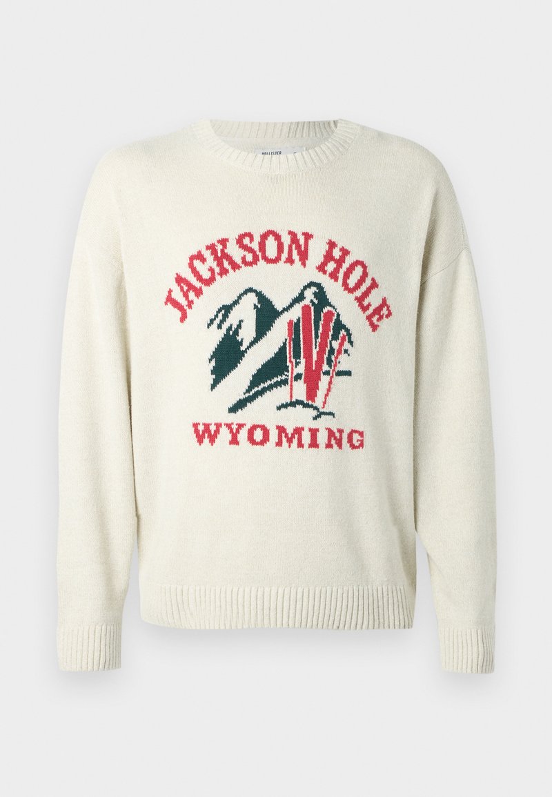 Helle Cremefarbenes Sweatshirt mit grober Strickstruktur. Besitzt ein grafisches Design mit "JACKSON HOLE" und "WYOMING" in Rot und Grün. Runde Halslinie.