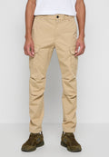 Beige Cargo-Hosen aus Baumwolle, mit zwei Seitentaschen, einer lockeren Passform und einem geraden Bein-Design. Kombiniert mit grünen Sportschuhen.