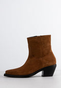 Braune Wildleder-Ankle Boots mit spitzem Zeh, schwarzem Blockabsatz und seitlichem Reißverschluss auf einem schlichten weißen Hintergrund.