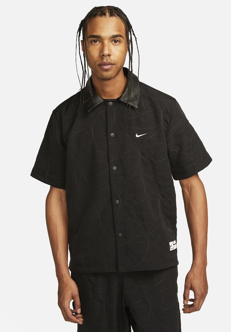 Schwarze Kurzarmjacke mit matter Oberfläche, tonalem Nähen und Lederkragen; verfügt über ein Nike-Logo auf der Brust und dem Saum.