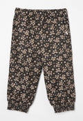 Schwarze Blumenhose mit elastischem Bund und gerafften Bündchen, die ein Muster aus kleinen beigen und weißen Blumen auf einem dunklen Hintergrund zeigt.