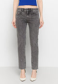 Graue Denim-Skinny-Jeans mit mittelhohem Bund, fünf Taschen und einer subtilen verblassten Textur, kombiniert mit weißen Absätzen.