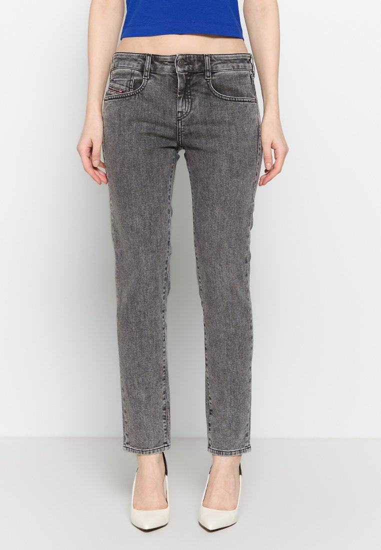 Graue Denim-Skinny-Jeans mit mittelhohem Bund, fünf Taschen und einer subtilen verblassten Textur, kombiniert mit weißen Absätzen.
