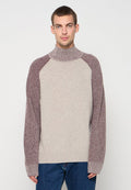 Gestrickter Pullover mit hohem Kragen, bestehend aus einem beigen Körper und kastanienbraunen, strukturierten Raglanärmeln, mit gerippten Bündchen und Saum. Lässige Passform.