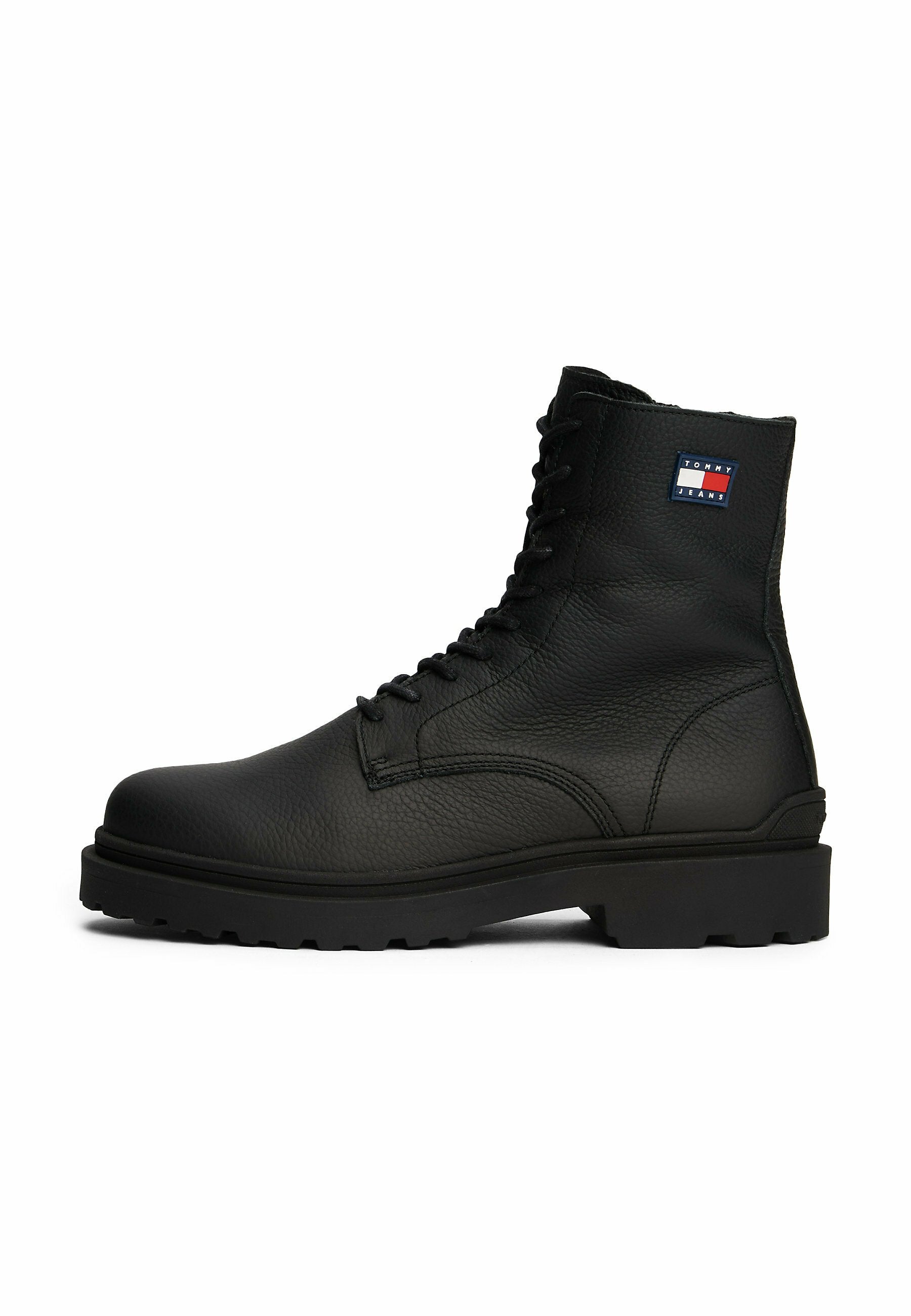 Schwarze Leder-Schnürstiefel mit strukturierten Oberflächen, robuster Gummisohle und einem kleinen rot-weiß-blauen Logo an der Seite.