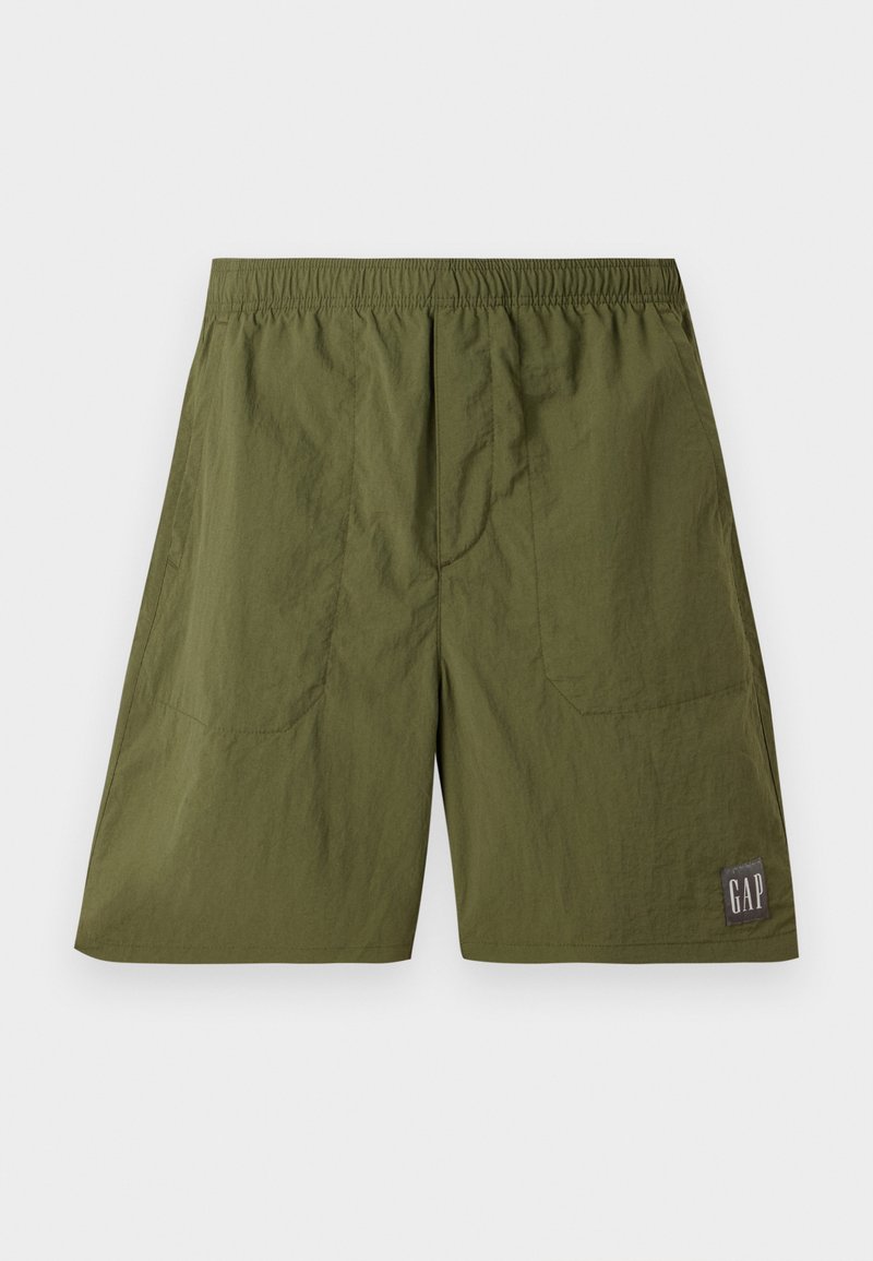 Grüne Nylonshorts mit einem elastischen Bund, zwei Seitentaschen und einem Aufnäher mit "GAP" in Weiß auf einem dunkelgrauen Hintergrund.