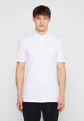 Mann trägt ein schlichtes weißes Kurzarm-Poloshirt mit Kragen, steht vor einem einfarbigen, hellen Hintergrund, Hände entspannt an den Seiten.