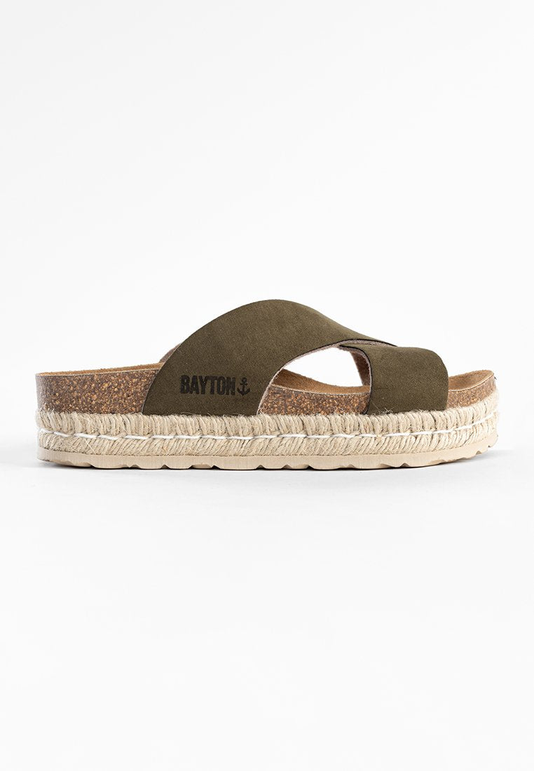 Grüne Wildleder-Sandale mit Kreuzriemen-Design, Kork-Mittelsohle und natürlicher Jute-Plattform. Markenlogo auf dem Riemen sichtbar.