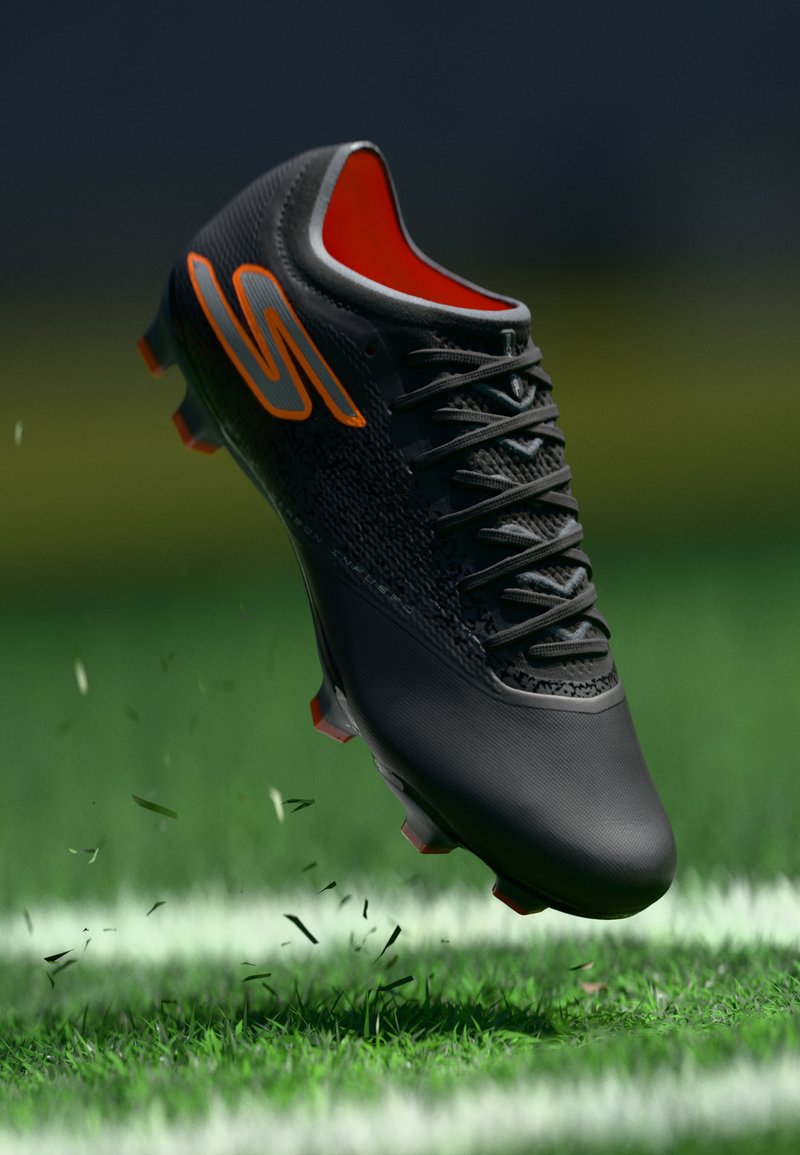 Schwarzer Fußballschuh mit orangenen Akzenten; strukturiertes Obermaterial, sichtbare Schnürsenkel und geformte Stollen auf einer grasbewachsenen Fläche, in der Luft schwebend.