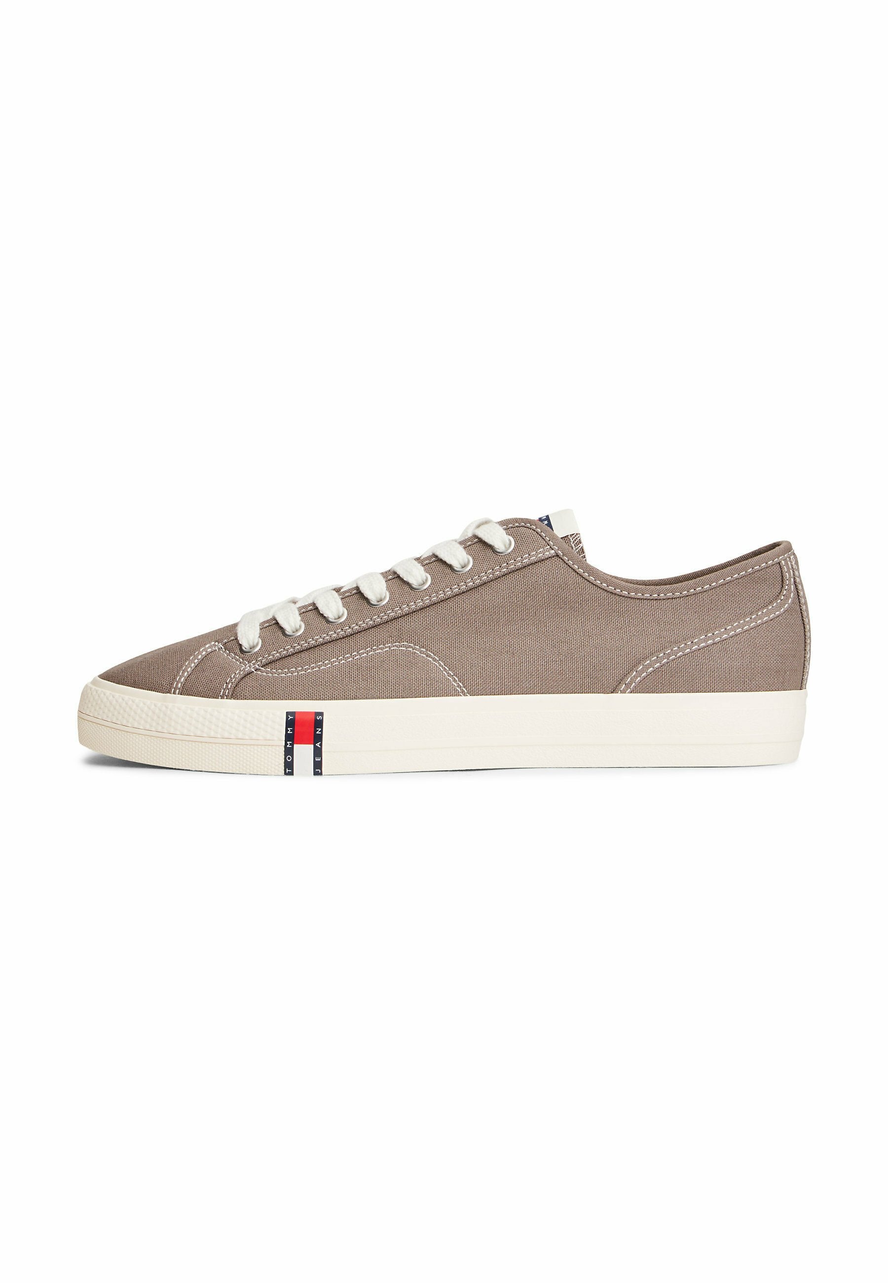 Niedriger Sneaker aus taupefarbenem Segeltuch mit weißen Schnürsenkeln, weißer Gummisohle und einem kleinen rot-weiß-blauen Logo an der Seite.