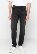 Schwarze Denim-Jeans mit geradem Bein, versehen mit verblassten Akzenten und klassischem Fünf-Taschen-Design. Eingerahmt mit weißen Sneakern.
