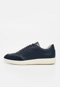 Herrensneaker aus dunkelblauem Leder mit schwarzer Velourkappe, weißem Innenfutter und weißer Gummisohle, Seitenansicht auf einfarbigem Hintergrund.