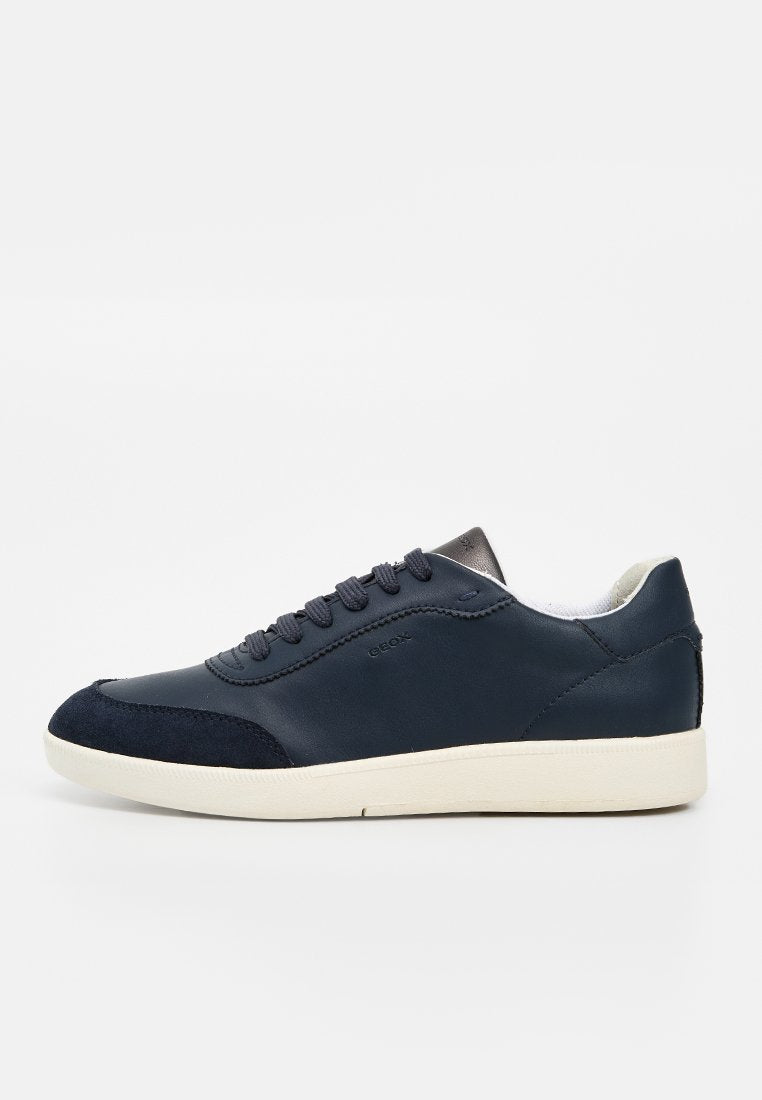 Herrensneaker aus dunkelblauem Leder mit schwarzer Velourkappe, weißem Innenfutter und weißer Gummisohle, Seitenansicht auf einfarbigem Hintergrund.