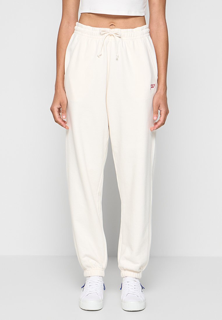 Cremefarbene Jogginghosen mit einem elastischen Bund und Bündchen. Verfügt über seitliche Taschen und ein rotes Logo-Detail an der Hüfte. Aus weichem Stoff gefertigt.