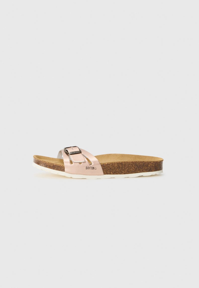 Flache Sandale mit einem metallischen pinken Riemen und silberner Schnalle, Korkfußbett, weißer Außensohle und dem Markennamen "BAYTON" an der Seite.