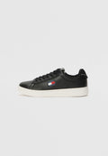 Schwarze Ledersneaker mit weißer Gummisohle, versehen mit einem Logo-Label in Rot, Weiß und Blau an der Seite und flachen schwarzen Schnürsenkeln.