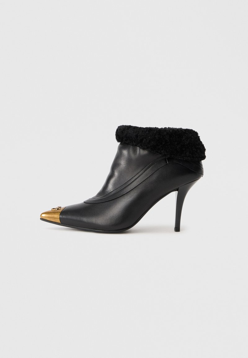 Schwarze Leder-Stiefelette mit einem strukturierten schwarzen Pelzkragen, spitzen goldenen Zehenkappe und einem schlanken Stiletto-Absatz. Verfügt über gestickte Designdetails.