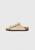 Hellbeige Wildledersandale mit zwei verstellbaren Schnallen, Korkfußbett und schwarzer Gummisohle für Griffigkeit. Minimalistisches Design.