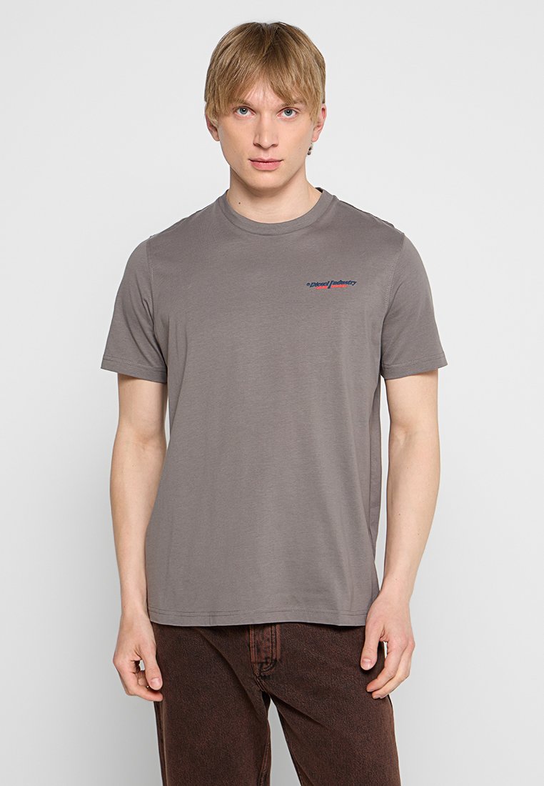 Graues Baumwoll-T-Shirt mit Rundhalsausschnitt und kurzen Ärmeln. Hat ein kleines, blau gedrucktes Logo auf der Brust. Glatte Textur.