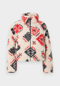 Sherpa-Zip-Up-Jacke mit hohem Kragen, cremefarbenem Grundton und einem Rautenmuster in Rot und Schwarz. Weiche Textur und puffy Silhouette.