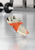 Leichte Sportschuhe in Creme, Orange und Schwarz. Sie verfügen über ein strukturiertes Obermaterial, ein schwarzes Swoosh-Logo und eine gemusterte Sohle für besseren Grip.