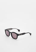 Schwarze Sonnenbrille mit quadratischem Rahmen, dunkellila Gläsern und einem kleinen silbernen Emblem an den Bügeln, vor weißem Hintergrund.