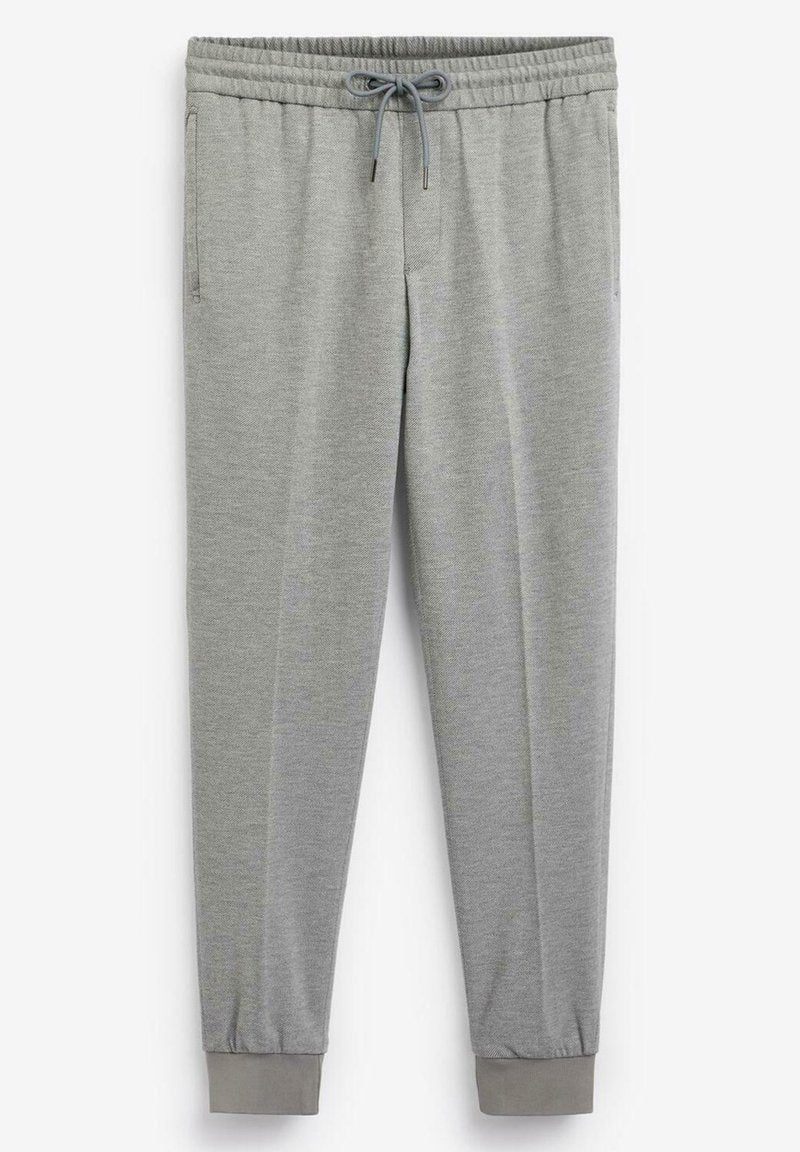 Graue Jogginghose aus weichem Stoff; elastischer Bund mit Kordelzug; schmal zulaufende Beine mit gerippten Bündchen; Seitentaschen.