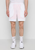 Mann trägt weiße Mesh-Sportshorts, weiße Nike-Socken und weiße Turnschuhe, steht vor einem schlichten hellgrauen Hintergrund.