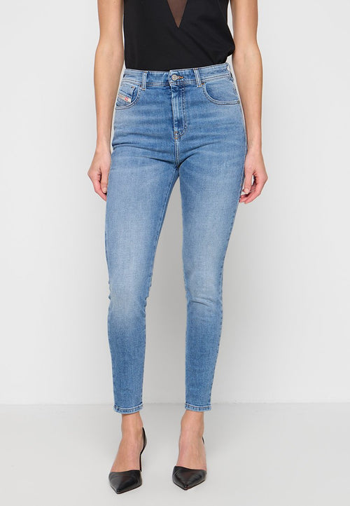 Frau trägt hellblaue High-Waist Skinny Jeans kombiniert mit schwarzen spitzen High Heels und einem ärmellosen schwarzen Oberteil.