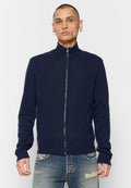 Navy Zip-Up-Pullover mit hohem Kragen, gerippten Ärmelbündchen und Saum, glatte Textur, aus weichem Strickmaterial, getragen über ausgewaschenen blauen Jeans.