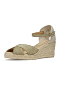 Grüne Keilsandalette aus Wildleder mit überkreuzten Riemen, Knöchelriemen und Absatz aus gewebtem Stoff. Espadrille-artige Sohle aus Seil mit strukturierten Details.
