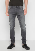 Graue Denim-Jeans mit Slim-Fit, ausgestattet mit einer ausgewaschenen Optik, klassischem Fünf-Taschen-Design und Reißverschluss, kombiniert mit schwarzen Slippern.