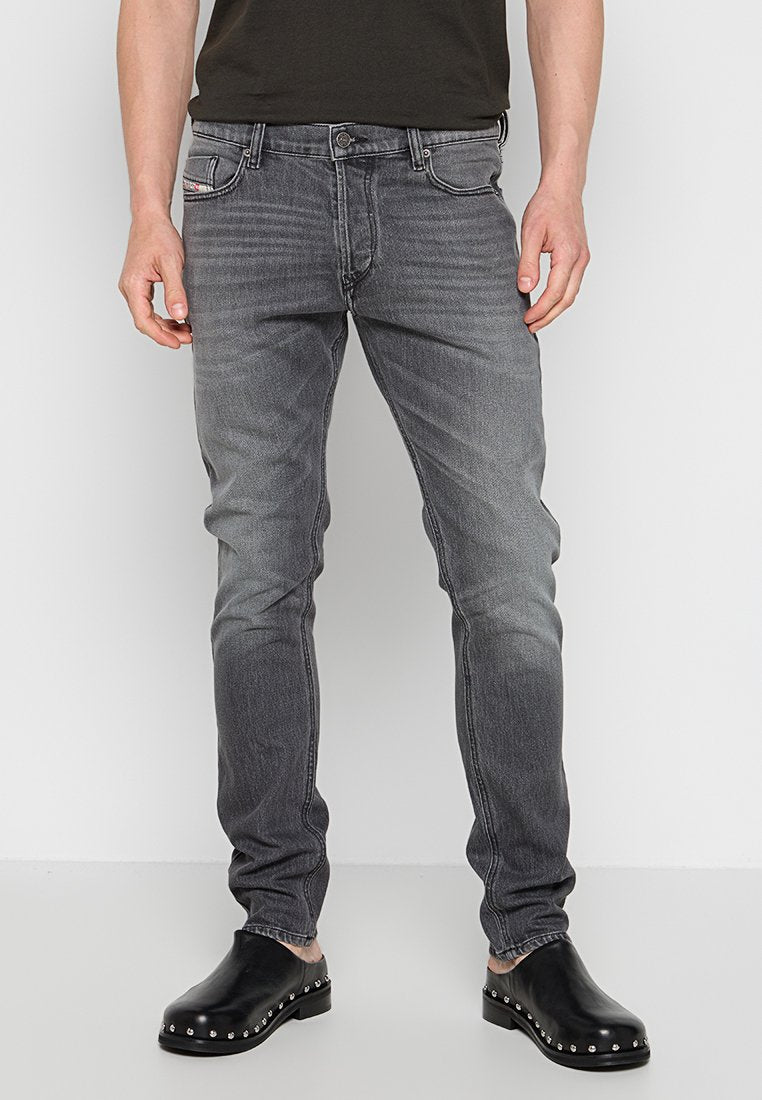 Graue Denim-Jeans mit Slim-Fit, ausgestattet mit einer ausgewaschenen Optik, klassischem Fünf-Taschen-Design und Reißverschluss, kombiniert mit schwarzen Slippern.