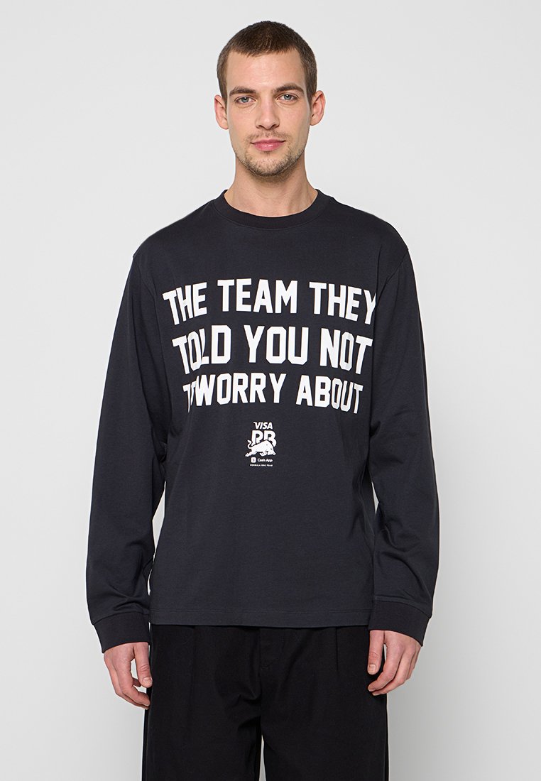 Schwarzes Langarm-T-Shirt mit markantem weißen Schriftzug, Rundhalsausschnitt und lockerem Schnitt. Enthält ein kleines grafisches Logo auf der unteren linken Seite.