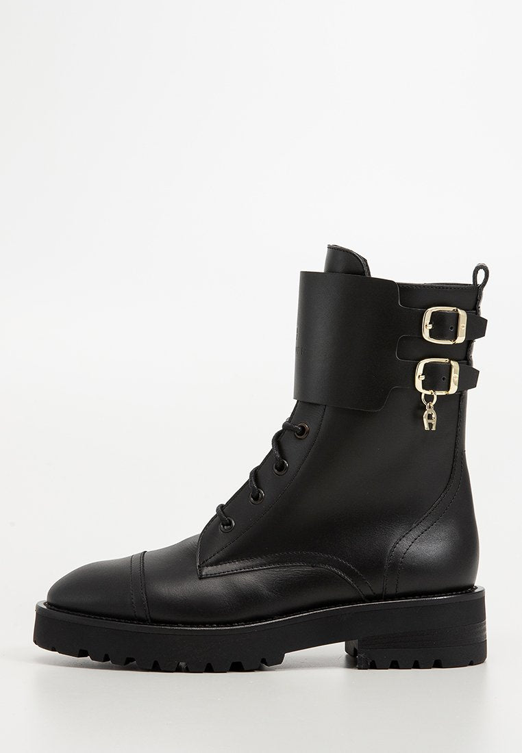 Schwarze Leder-Stiefelette mit runder Zehenpartie, Schnürung vorne, zwei dekorativen Schnallenriemen und einer dicken, profilierten Sohle.