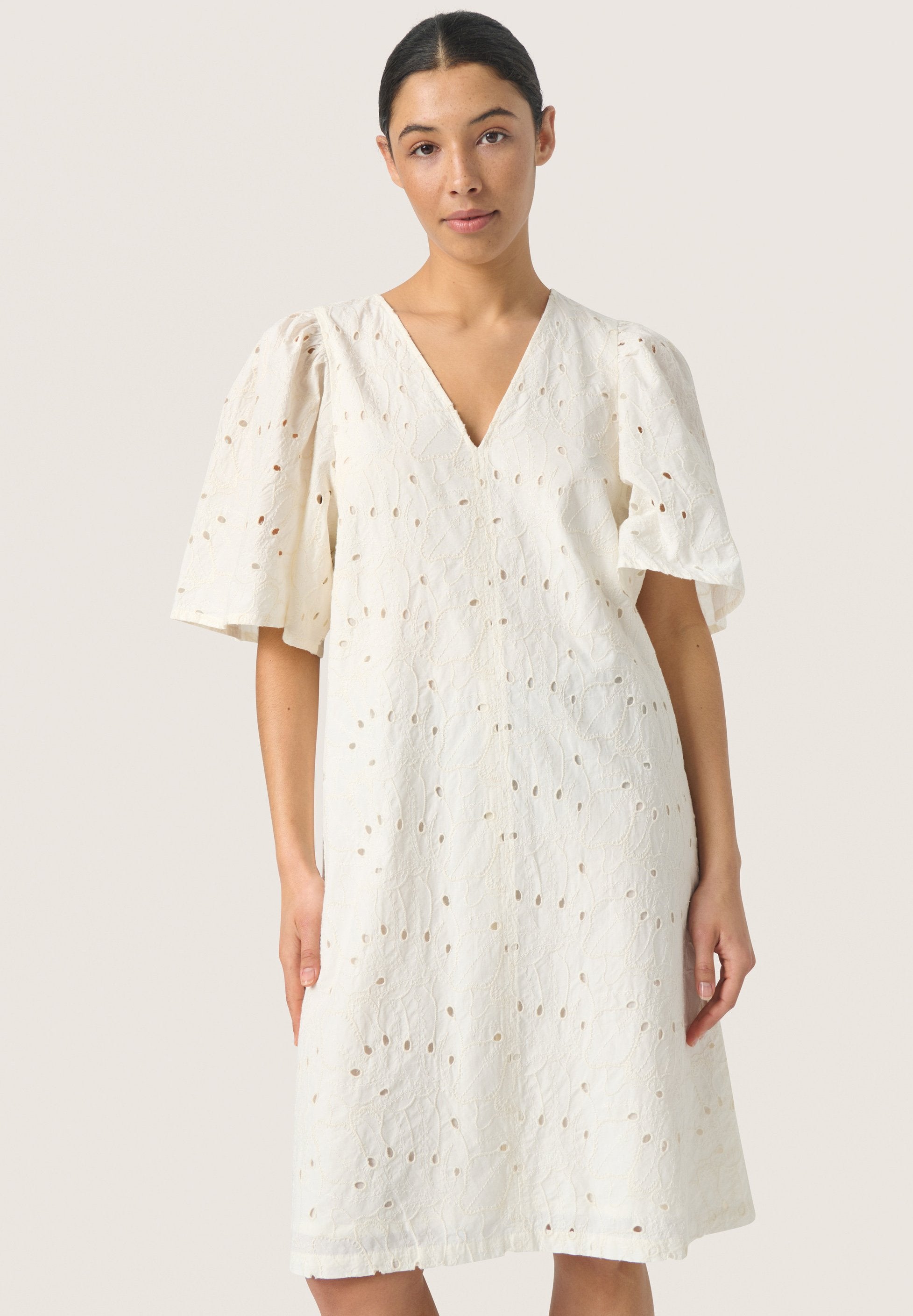Weißes knielanges Kleid mit Puffärmeln, V-Ausschnitt und strukturiertem Stoff mit kleinen Lochmustern. Lässiges und fließendes Design.