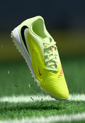 Leuchtend gelber Fußballschuh mit strukturierter Oberfläche, roten Akzenten und schwarzem Logo. Leichtes Design, Stollensohle und Schnürverschluss.