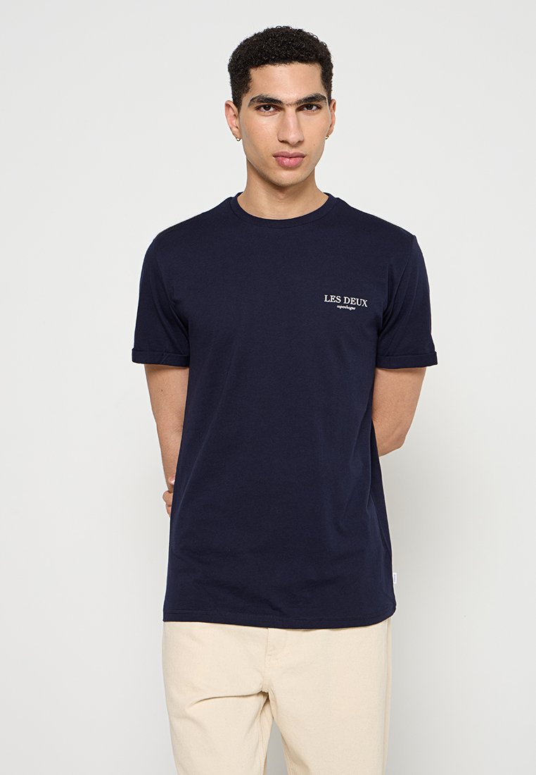 Navy-blaue Baumwoll-T-Shirt mit kurzen Ärmeln, rundem Halsausschnitt und einem weißen Brustlogo "LES DEUX". Sanfte Textur, normale Passform.