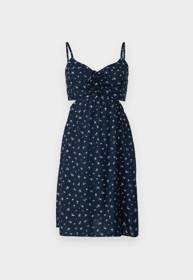 Marineblaues Blumenkleid mit tailliertem Oberteil, verstellbaren Spaghetti-Trägern und geraffter Taille, das kleine weiße Blumenmuster aufweist.